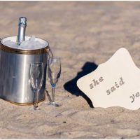 Champagne and sign for marriage proposal on beach