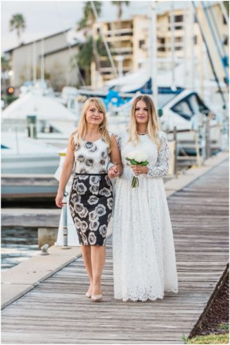 Mother walking daughter down isle at Chart House waterfront Wedding