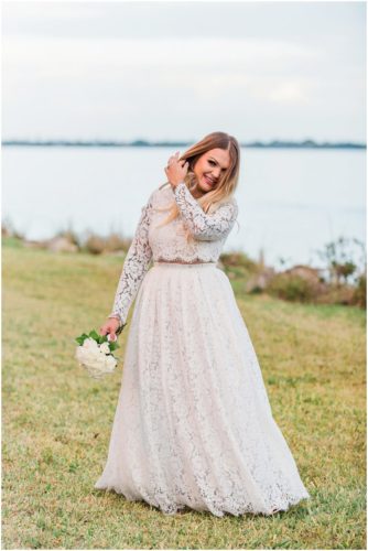 Bride in lace dress by water at waterfront wedding at Chart House