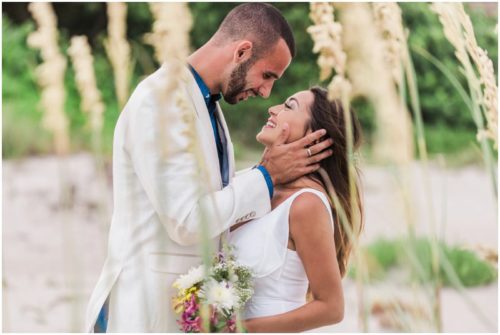 Bride and groom kissing by sea oats at beach elopement at Windemere by the Sea