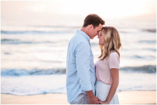 couple standing forehead to forehead couple walking down the beach during sunrise engagement on Melbourne Beach
