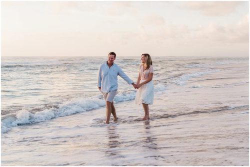 couple playing in the water couple walking down the beach during sunrise engagement on Melbourne Beach