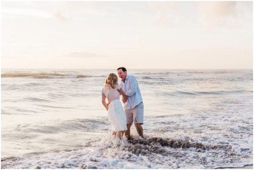couple playing in the water couple walking down the beach during sunrise engagement on Melbourne Beach