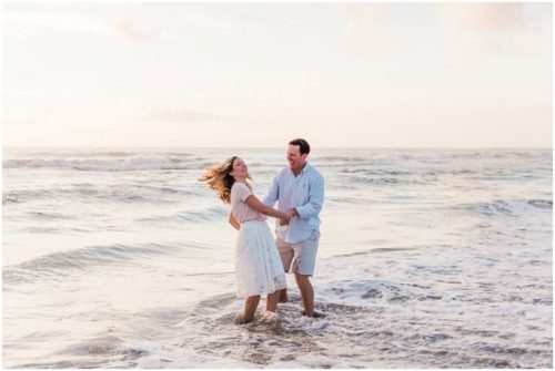 couple playing in the water couple walking down the beach during sunrise engagement on Melbourne Beach