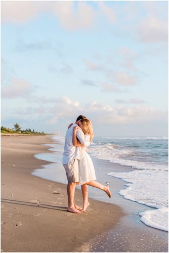 couple hugging on beach couple walking down the beach during sunrise engagement on Melbourne Beach