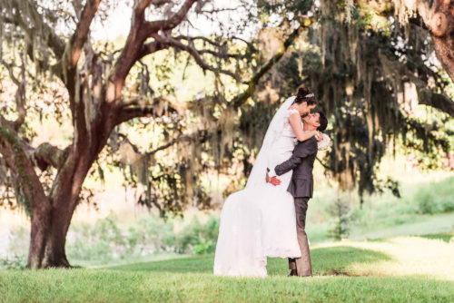 Orlando Wedding groom holding bride under Oak Trees photo by Liz Cowie Photography