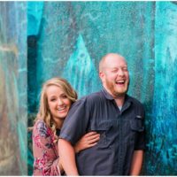 couple laughing behind blue wall at Melbourne engagement photography session