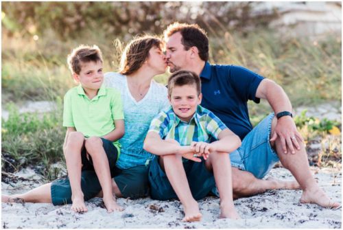 family with two boys sitting by dunes during Melbourne Beach Family Photography session