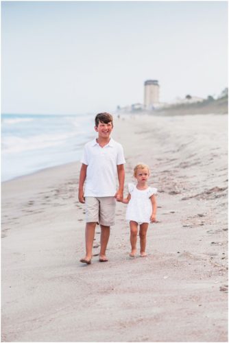 Siblings holding hands walking down beach during Melbourne Beach Family Portraits