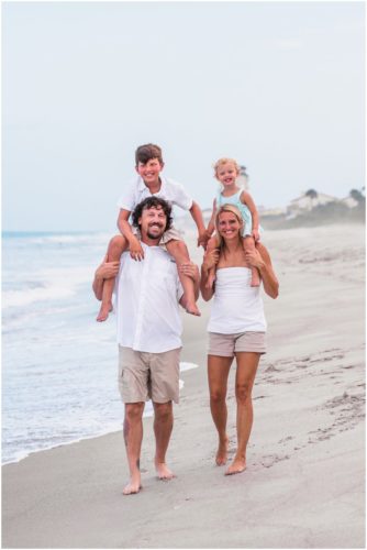 Mom and Dad giving kids piggy back rides during Melbourne Beach family portrait session