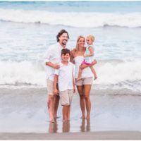 family with ocean waves crashing behind them during Melbourne Beach family portraits