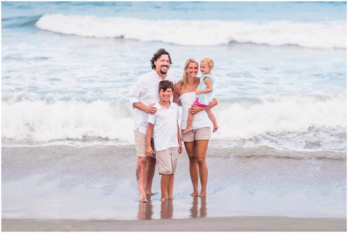 family with ocean waves crashing behind them during Melbourne Beach family portraits
