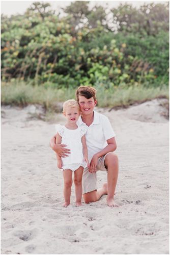 Siblings sitting with dunes in the background during Melbourne Beach Family Portraits