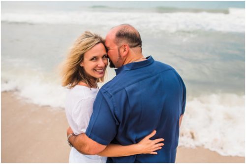 Mom laughing near the edge of the water during their fun family beach portraits