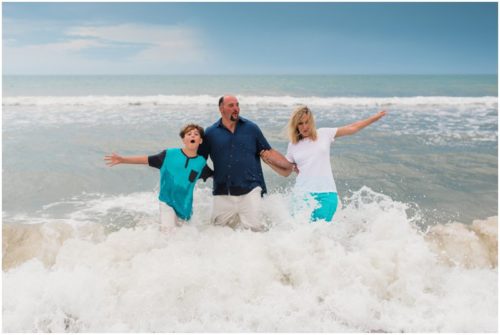 Big wave crashing on family during their fun family beach portraits