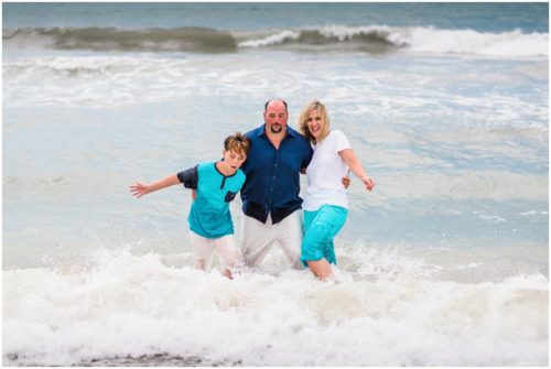 Family in water with waves crashing during their fun family beach portraits