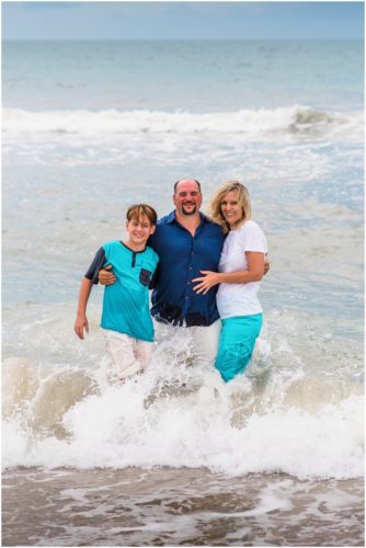 Family in water with waves crashing during their fun family beach portraits