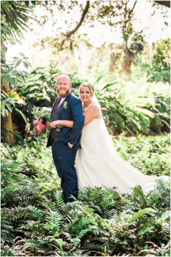 Bride behind groom with red flowers at Up the Creek Farms Wedding