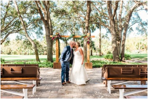 Bride and groom kissing in front of ceremony location at Up the Creek Farms Wedding