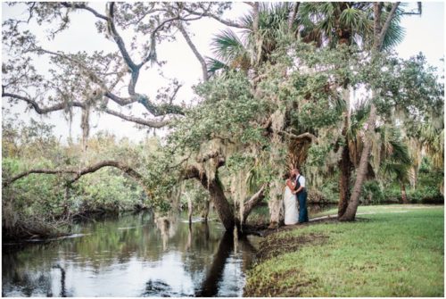 Bride and groom by the river under a tree at Up the Creek Farms Wedding
