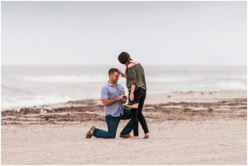 Groom proposing on one knee with ocean in background during Cocoa Beach Proposal