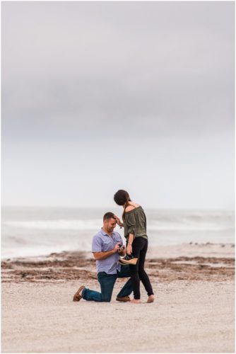 Groom proposing on one knee with ocean in background during Cocoa Beach Proposal