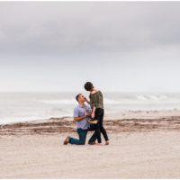Groom proposing on one knee with ocean in background during Cocoa Beach Proposal