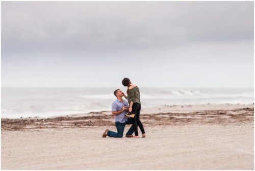 Groom proposing on one knee with ocean in background during Cocoa Beach Proposal