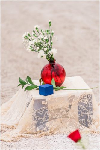 ring box and red vase on beach during Cocoa Beach Proposal