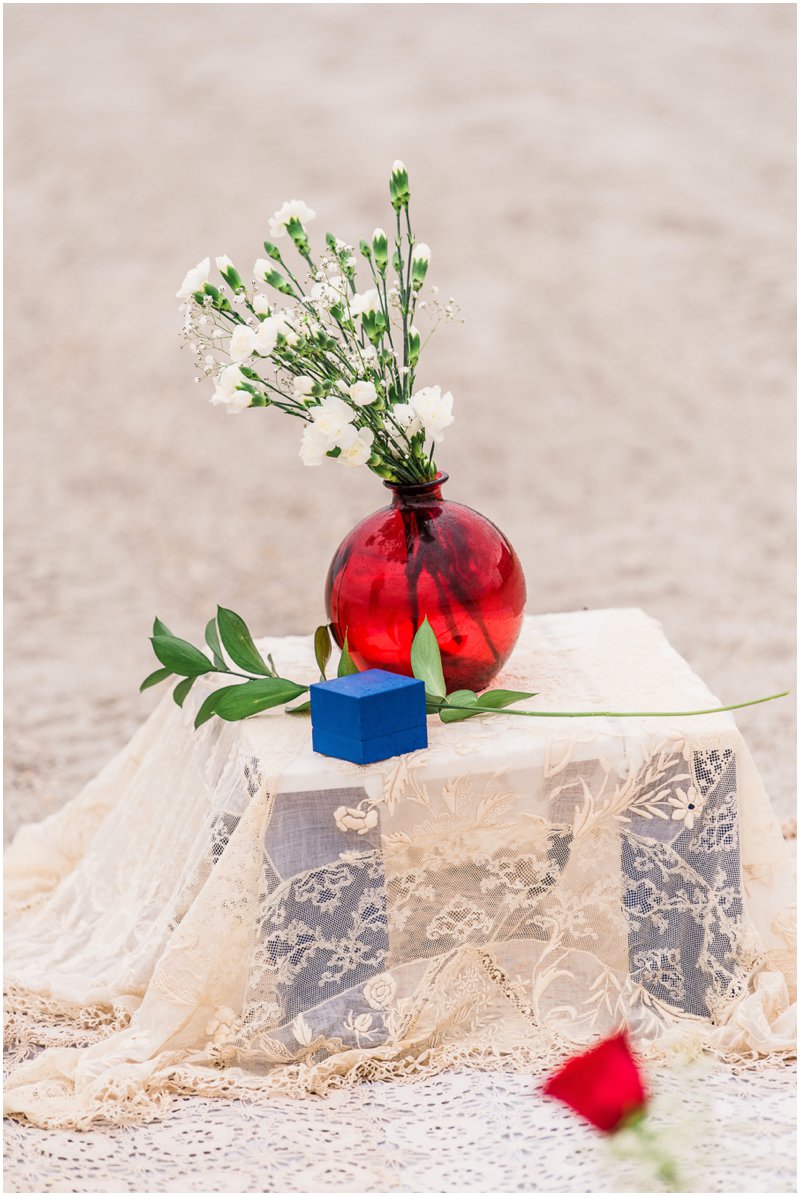 ring box and red vase on beach during Cocoa Beach Proposal