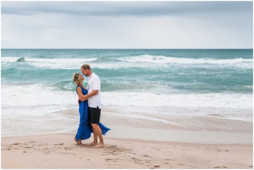 Couple hugging in water with waves crashing during storm beach engagement