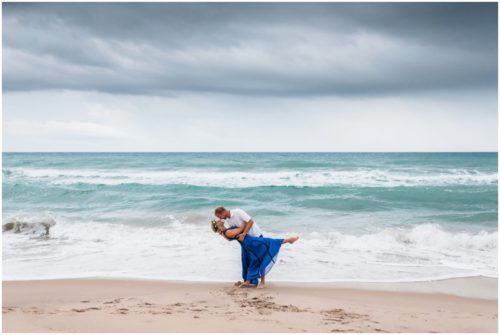 Couple on beach dipping with storm approaching during melbourne beach engagement session.