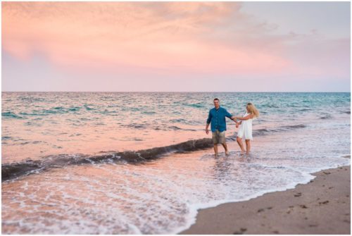 Couple walking in ocean during sunset beach engagement