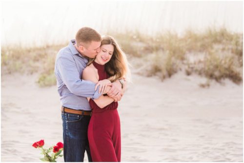 Couple hugging by dunes during Cocoa Beach Surprise Proposal