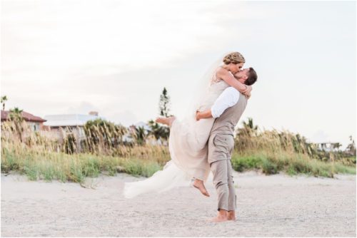 Groom hold ing up bride by the dunes Cocoa Beach Wedding