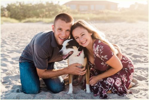 couple snuggling with dog on beach Melbourne Florida engagement photographer