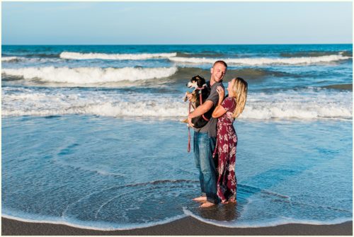 couple holding dog by water Melbourne Florida engagement photographer