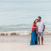 Waves rolling in as couple cuddles on beach Melbourne Beach Engagement Photography