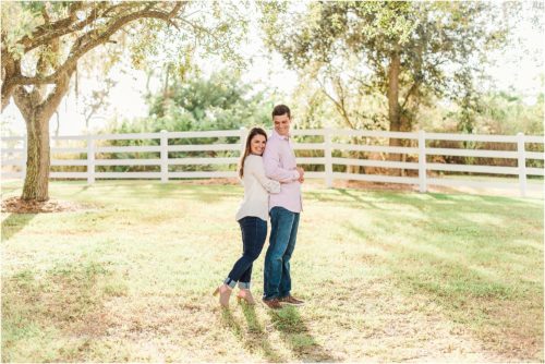 Couple hugging with white fence during Up the Creek Farms Engagement photography