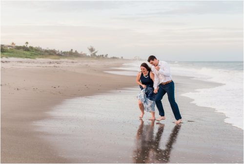 couple running from waves engagement photography