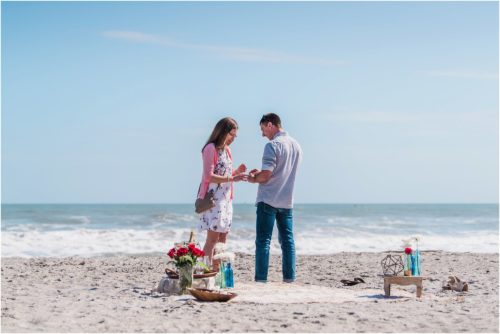 man putting on ring with ocean in the background during a Florida Beach Proposal