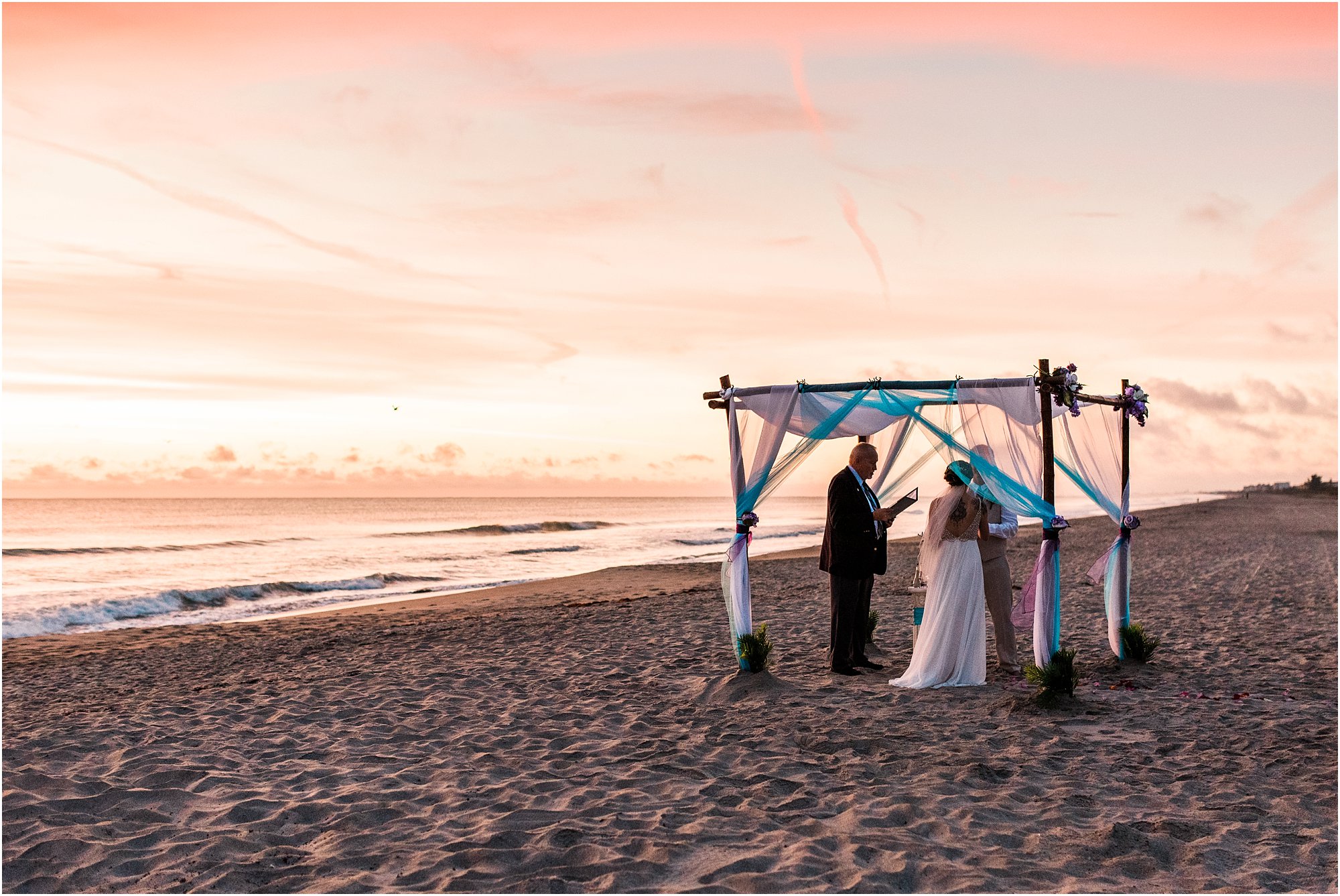 Bride and groom under blue and purple arch during Cocoa Beach Sunrise Wedding