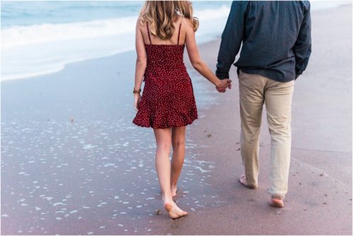 Couple walking hand in hand on beach during Floridana Beach engagement