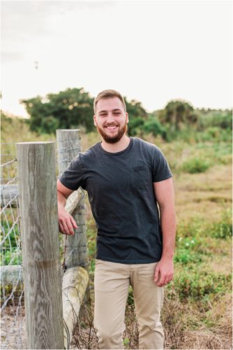 Groom by a fence during Floridana Beach engagement
