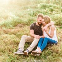 couple cuddling in field during Floridana Beach engagement