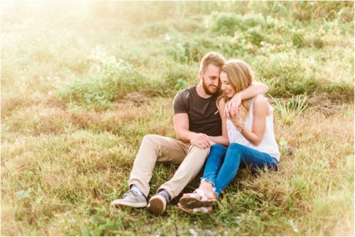couple cuddling in field during Floridana Beach engagement