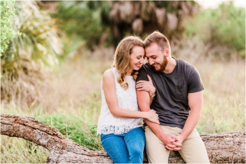 Couple sitting on log during Floridana Beach engagement