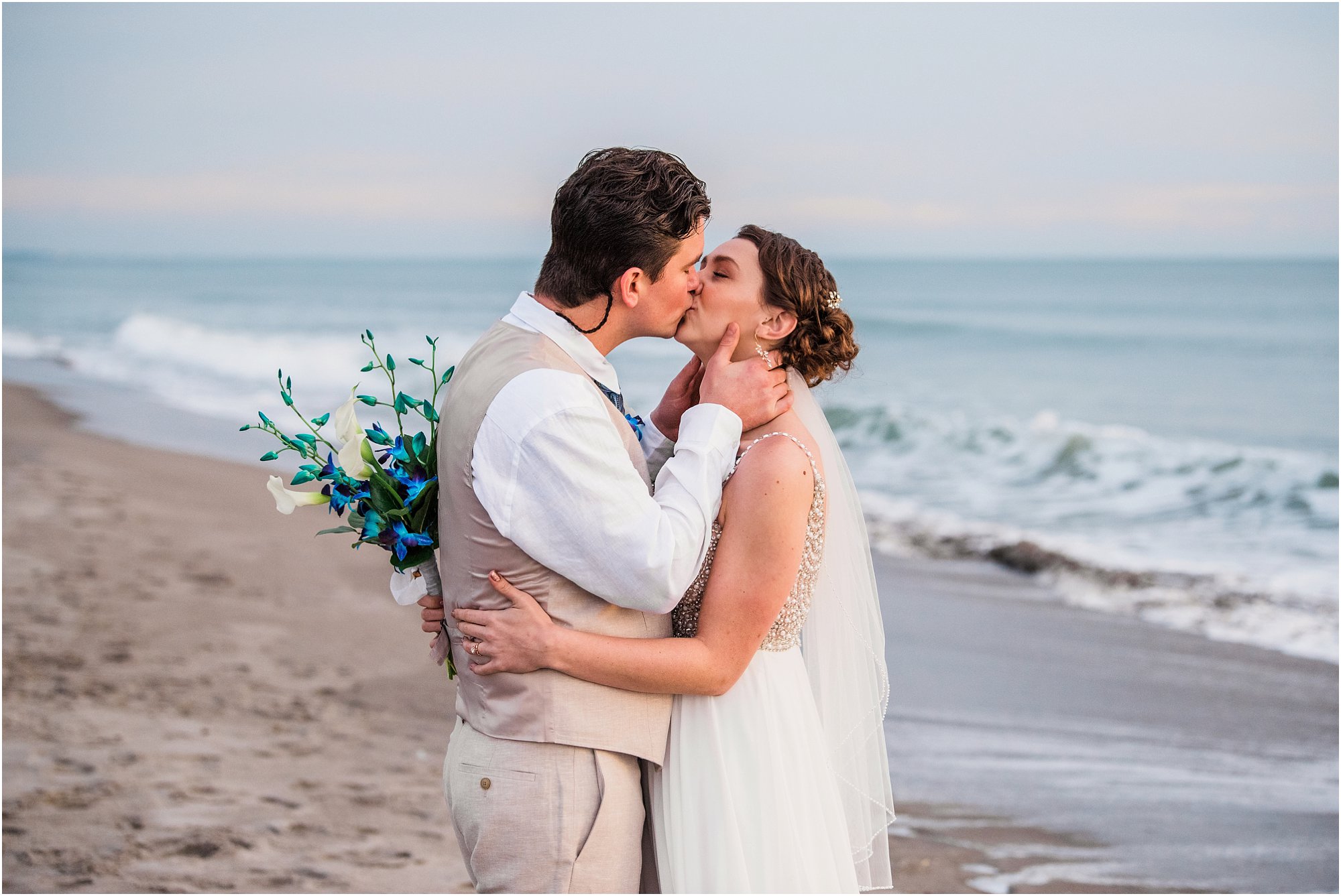 Bride and groom kissing by edge of water during Cocoa Beach Sunrise Wedding