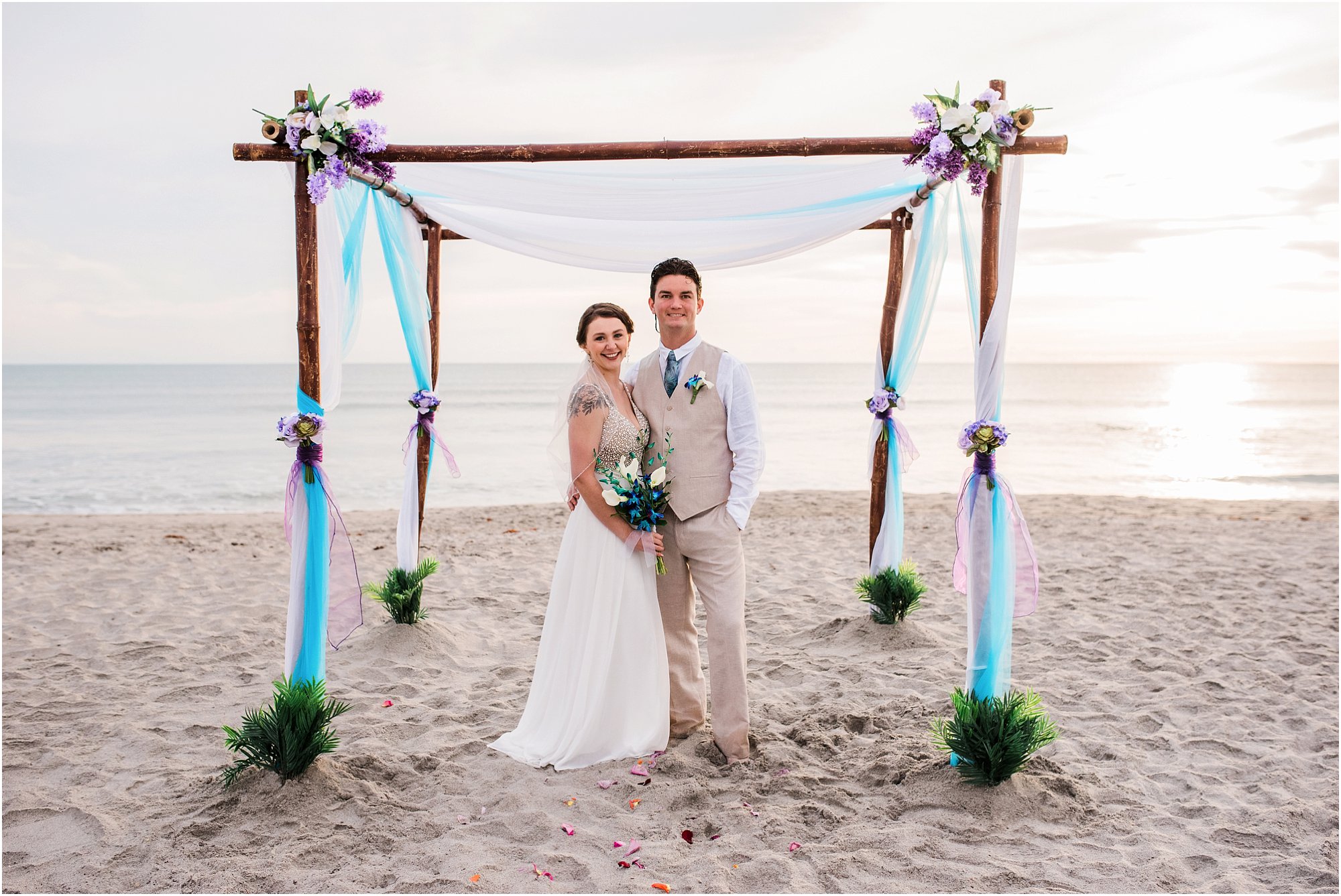 Bride and groom in front of blue and purple arch during Cocoa Beach Sunrise Wedding
