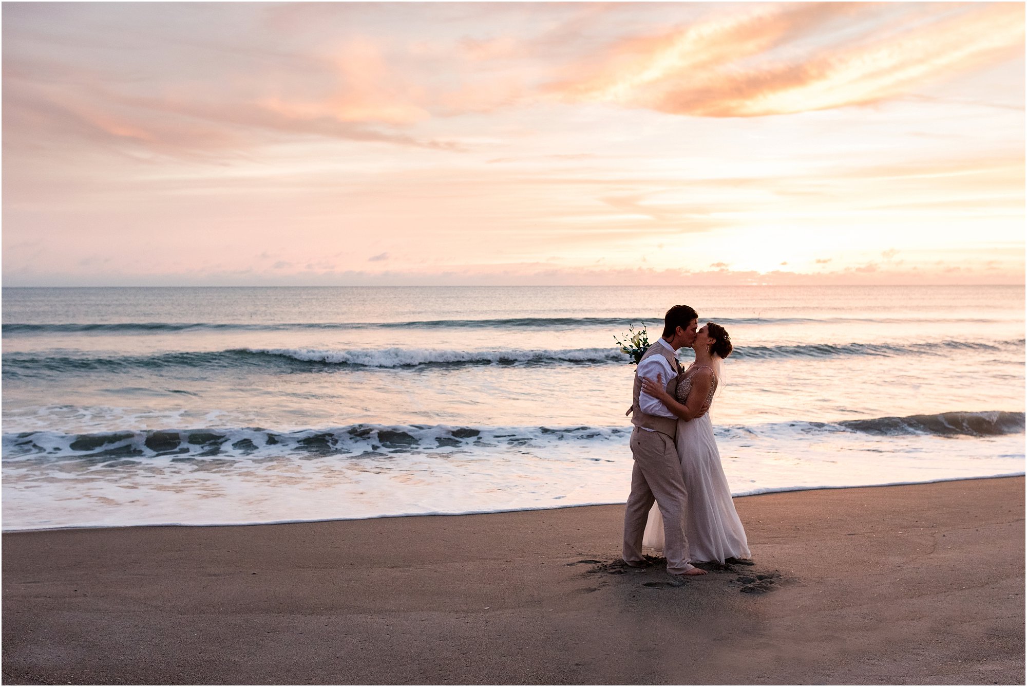 Bride and groom kissing by edge of water during Cocoa Beach Sunrise Wedding